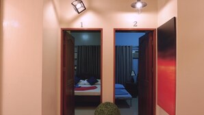 A hallway with two doors leading to bedrooms, each with a bed, curtains, and a nightstand. - Mactan Cebu Waiting Lounge (Lapu-Lapu)