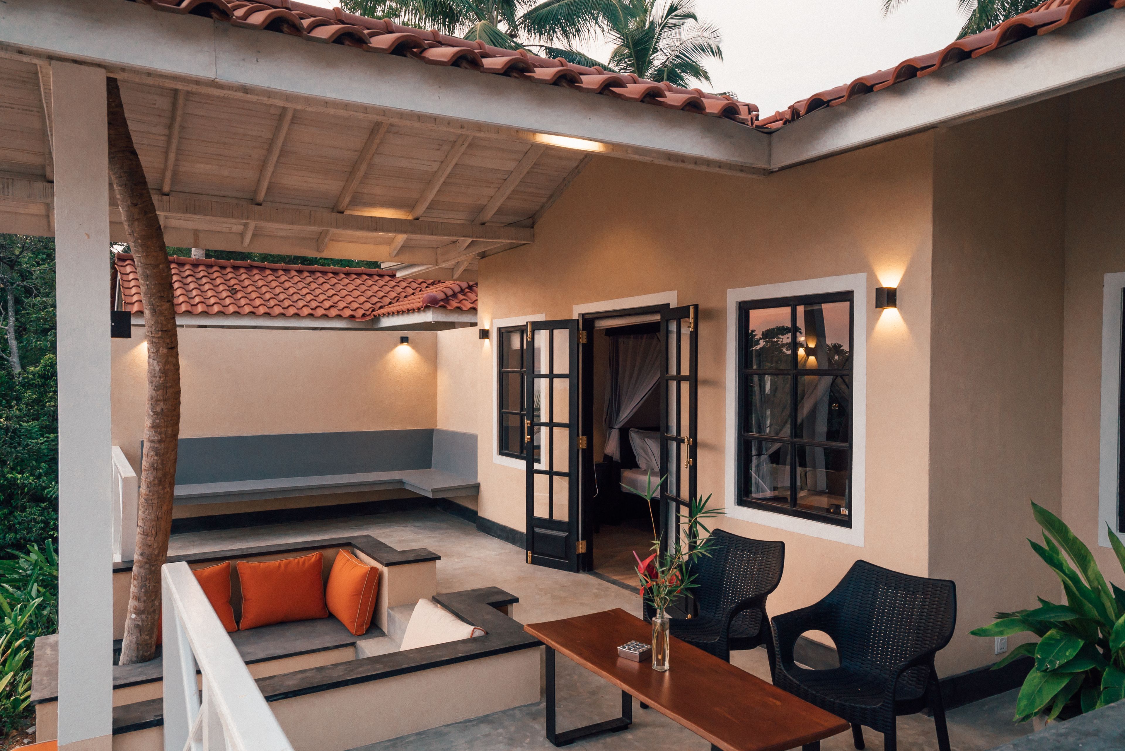 Un espace extérieur aménagé avec une table en bois, deux chaises et des coussins orange.
