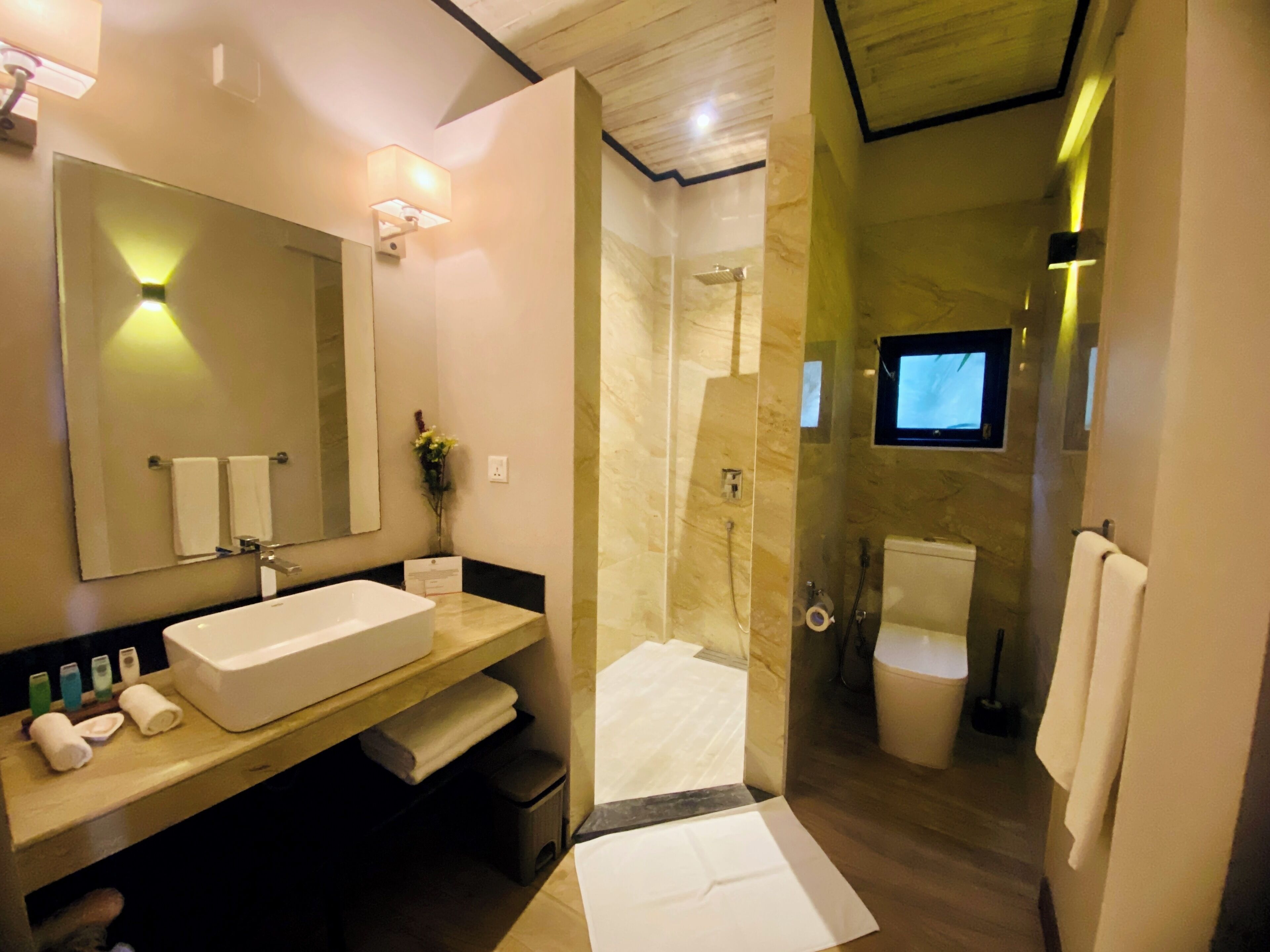 A modern bathroom with a large mirror, a sink, a shower, and a toilet.
