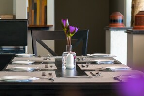A dining table set with plates, cutlery, and a vase with flowers.