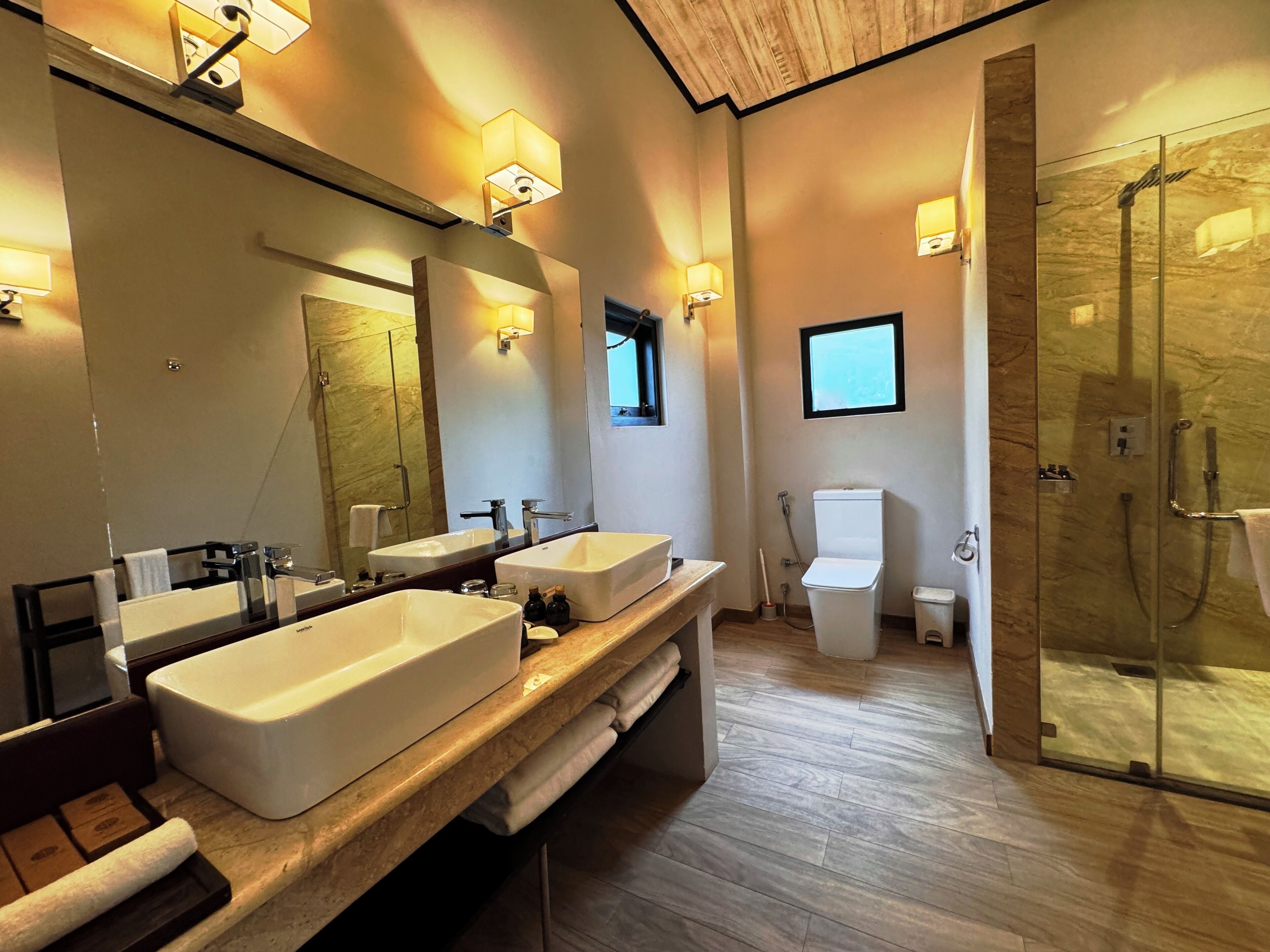 A modern bathroom with two large sinks, a glass shower enclosure, and a large mirror.