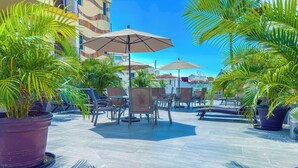 An outdoor patio area with seating, umbrellas, and potted plants. - Boana Torre Malibu #002 , street view romantic zone (Amapas)