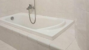 A bathroom with a white bathtub, a showerhead, and a glass shelf. - Agrigento Templi Pool Garden (Camastra)