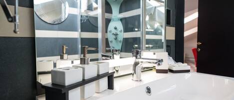 Ein modernes Badezimmer mit einem großen, weißen Waschbecken, zwei Spiegeln und einer dekorativen Vase.