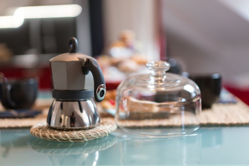 A coffee maker on a table with a glass container and a cup.