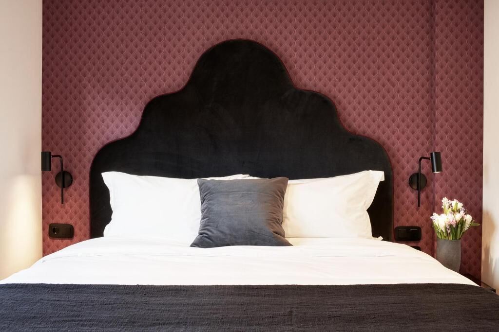 A bed with a dark headboard, white and gray pillows, and a dark bedspread.