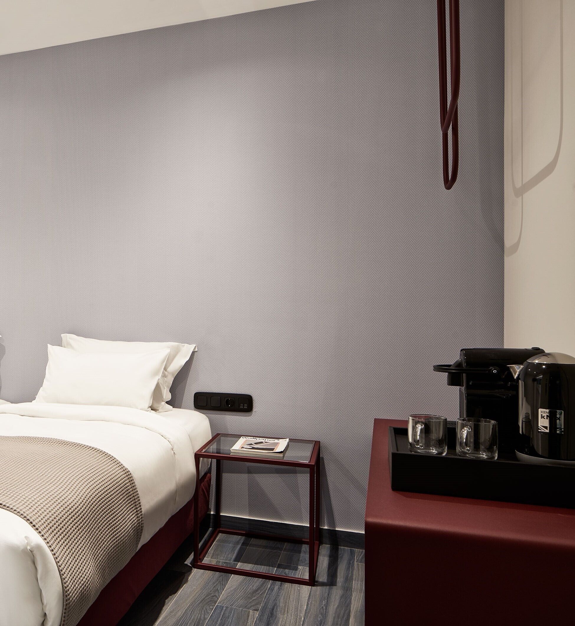 Quarto de hotel moderno com cama, mesa de cabeceira e cafeteira.