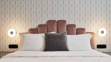 A neatly made bed with a headboard, two bedside lamps, and a patterned wallpaper.