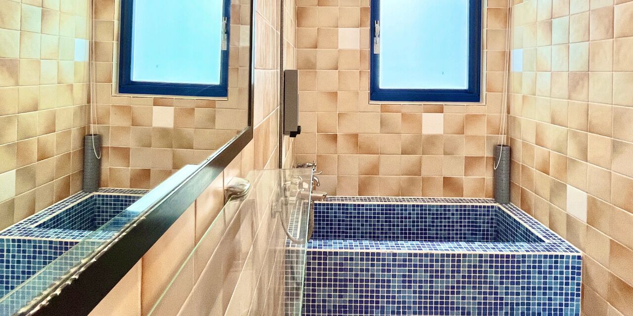 A bathroom with two sinks, tiled walls, and a window.