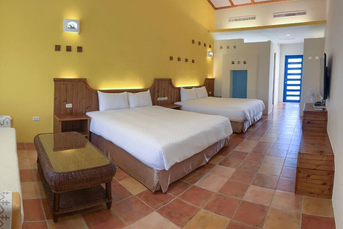 A hotel room with two beds, a sofa, a small table, and a TV.