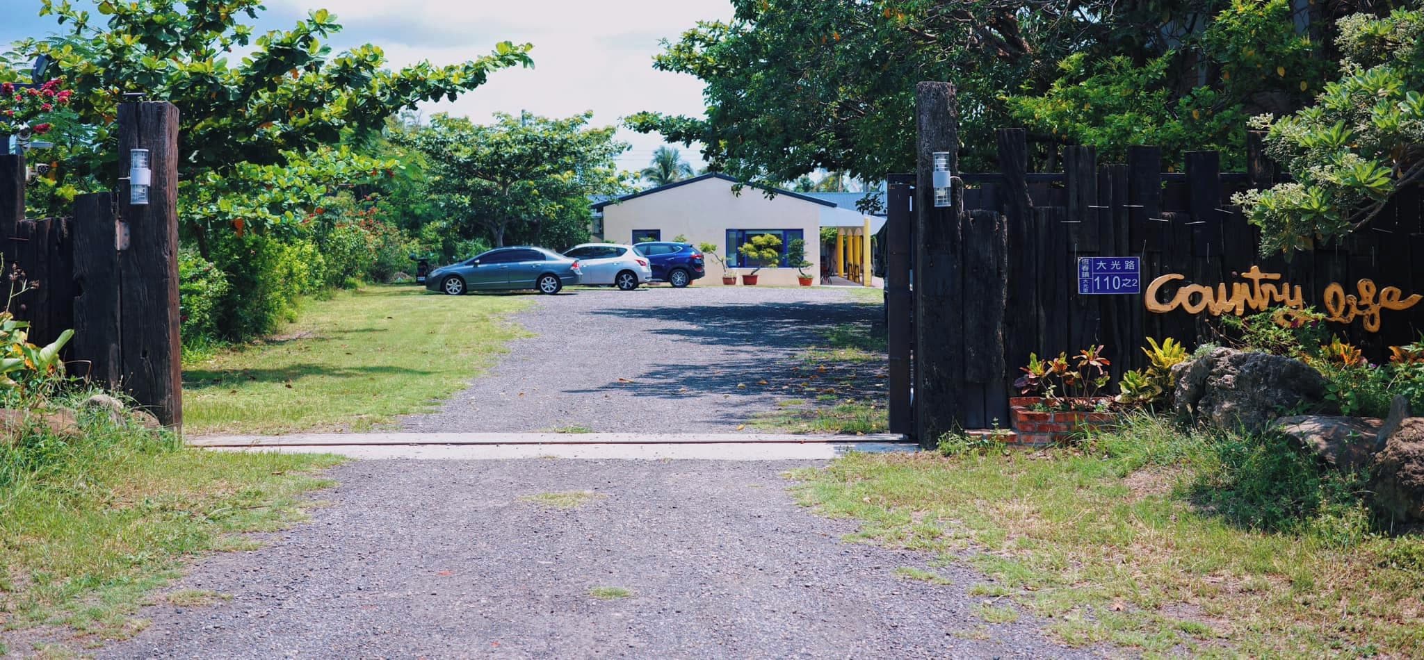 A gated entrance to a property with a gravel driveway leading to a building.