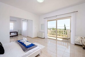 Une chambre spacieuse avec un grand lit, un balcon offrant une belle vue et un coin salon séparé.