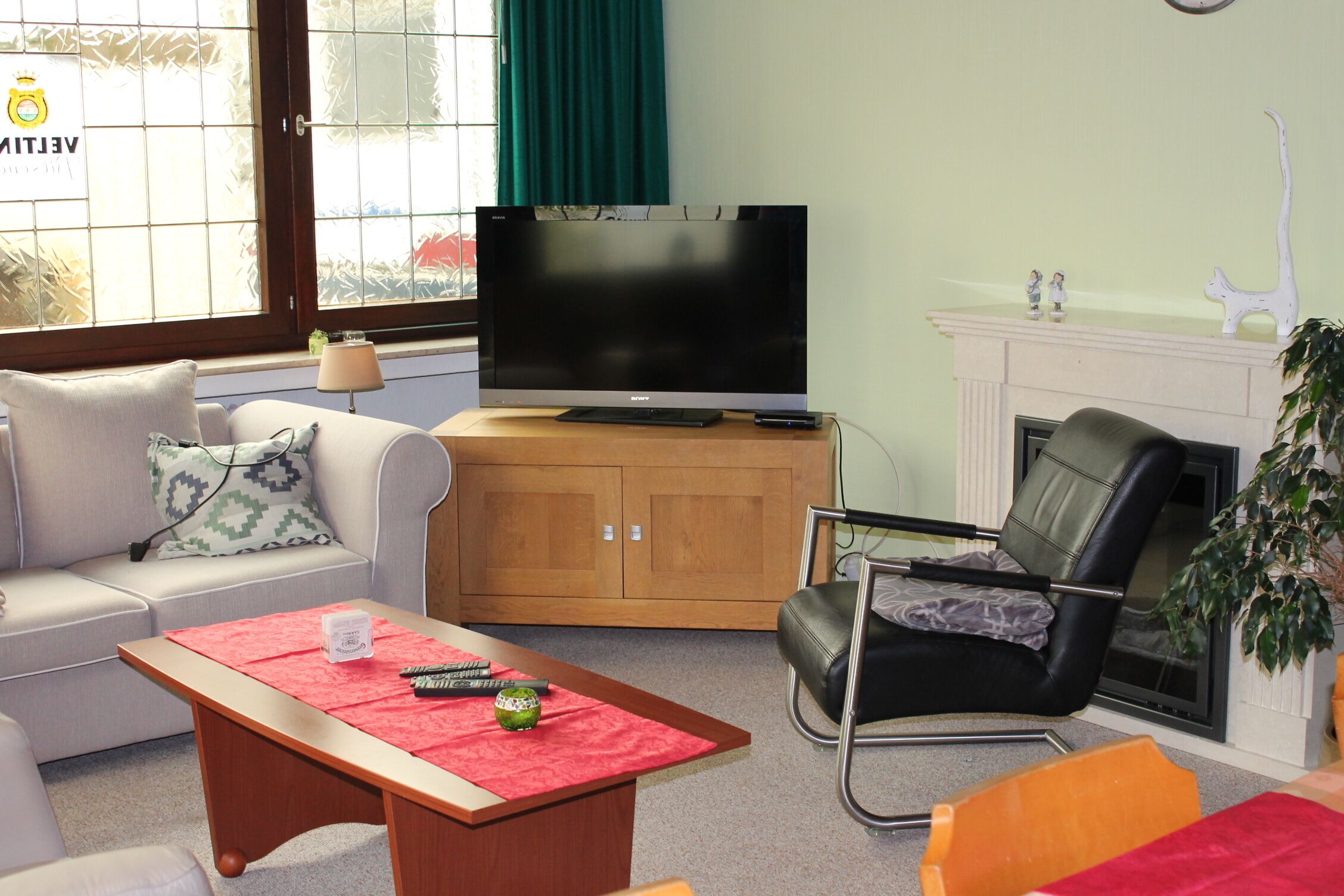 A living room with a sofa, a coffee table, a television, a fireplace, and a chair.