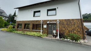 A two-story building with a sign 'Haus Gellen' above the entrance. There are two windows on the ground floor and a door with a small porch area. - Hotel Haus Erlen (Olsberg)