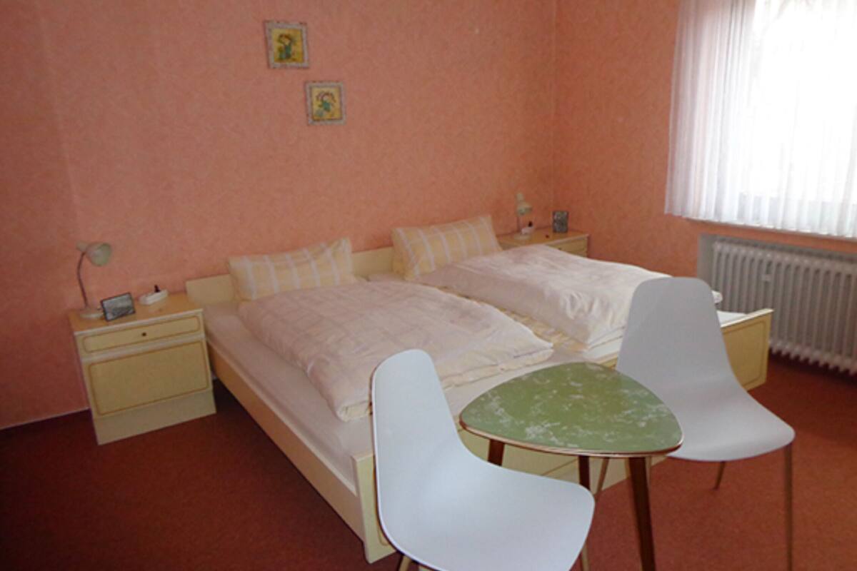 A bedroom with two beds, a small table, and two chairs.