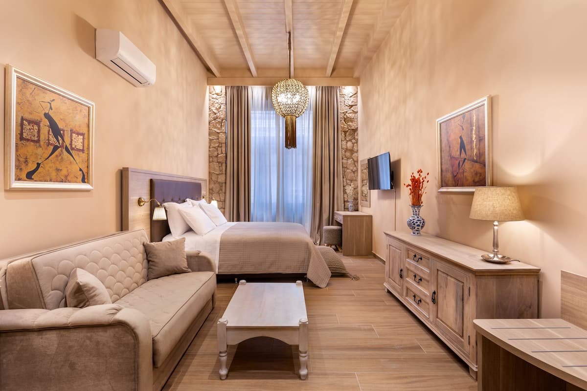 Une chambre d’hôtel moderne avec un grand lit, un canapé, une table basse et un téléviseur.