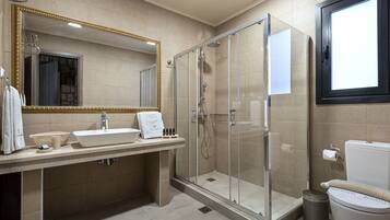 Een moderne badkamer met een grote spiegel, een douche met glazen wanden, een wastafel en een toilet.