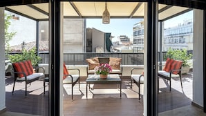 A balcony with wicker furniture, a glass table, and a potted plant. - Athens Manor Houses Suites Apartments (Athens)