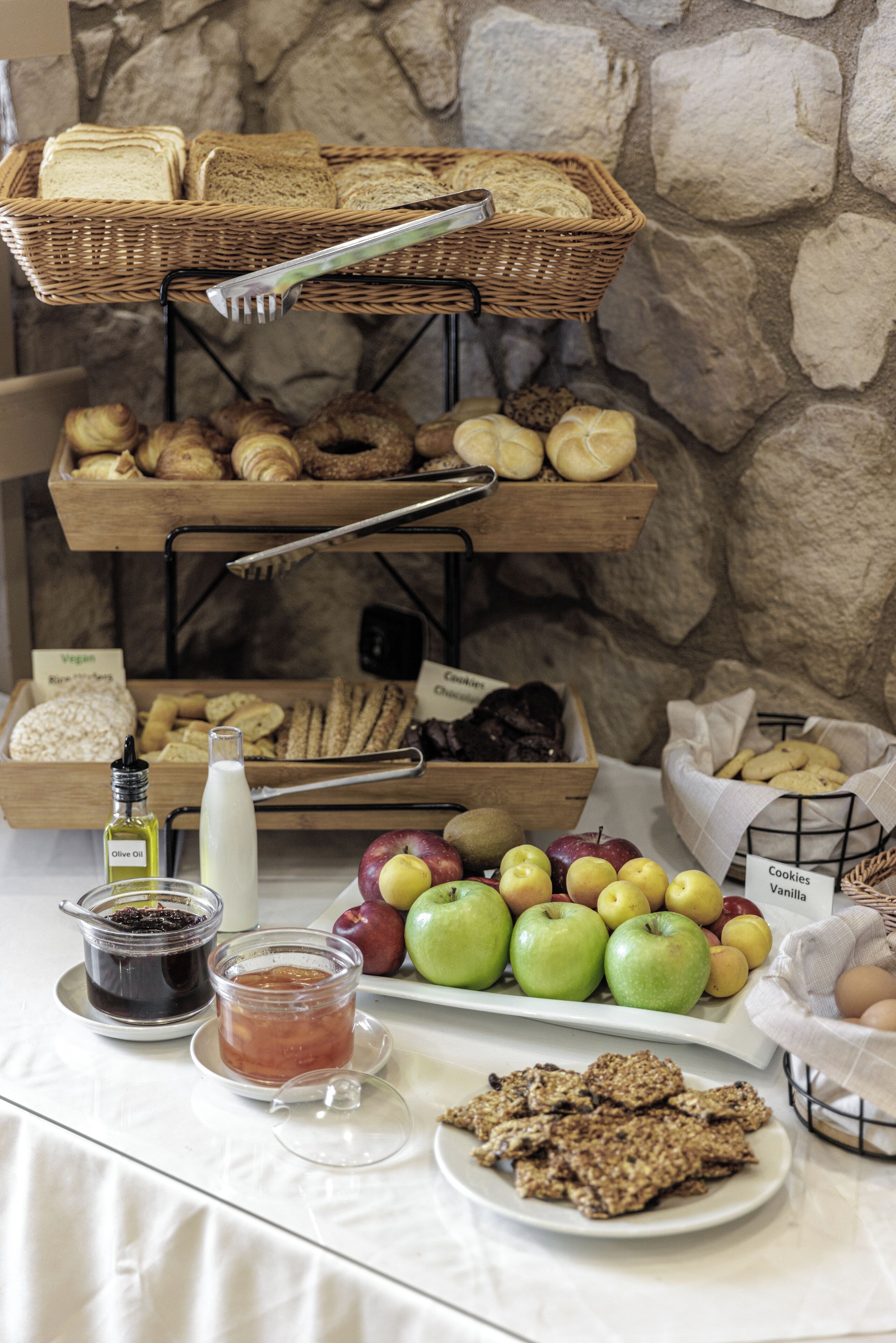 A breakfast buffet with bread, pastries, fruits, and beverages.