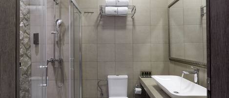 A modern bathroom with a glass-enclosed shower, a toilet, a sink, and a towel rack.