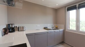 Une cuisine moderne avec un plan de travail blanc, des appareils en acier inoxydable et des meubles gris.