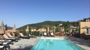 Una piscina al aire libre de temporada, sombrillas