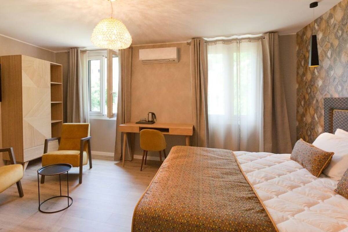 A hotel room with a bed, a desk, a chair, a TV, and a wardrobe.