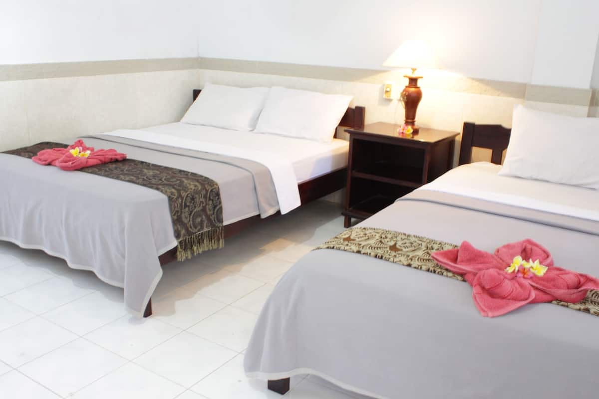 Two single beds with white linens and floral arrangements, a nightstand with a lamp, and a tiled floor.