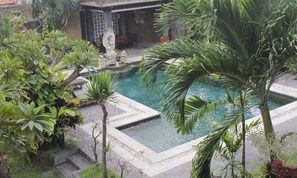 A pool surrounded by tropical plants and a stone pathway. - Mangga Bali Inn (Kuta)
