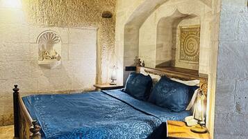 A room with a bed, a nightstand, a lamp, and a cowhide rug.