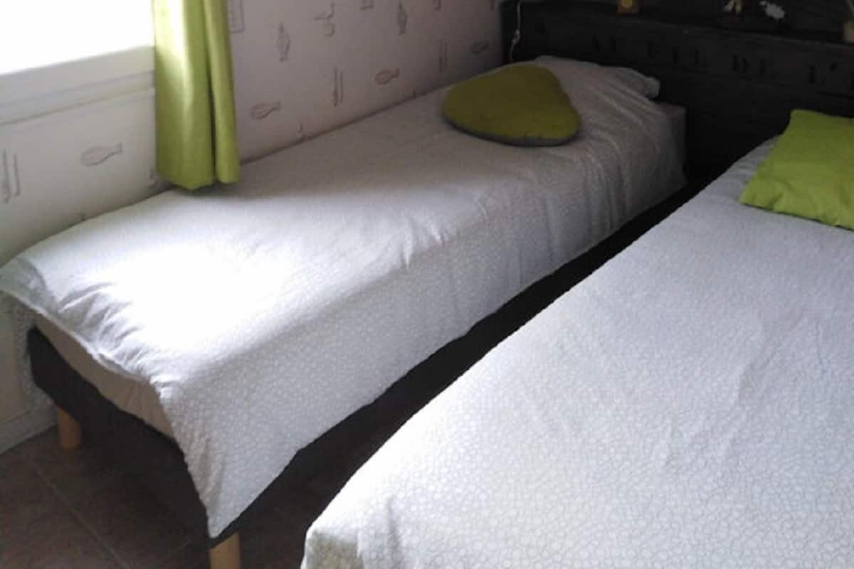Ein Schlafzimmer mit zwei Einzelbetten, einer Steinwand und einem Fenster mit Vorhängen.