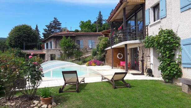 Une maison avec une piscine, un patio couvert et un jardin agrémenté de plantes en pot.