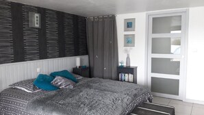 Une chambre à coucher avec un lit, une table de chevet, une bibliothèque, une porte et une fenêtre.