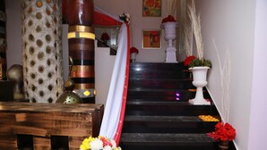 A staircase with red and white drapes, a wooden bench, and floral decorations. - Hotel Western Court (Panchkula)