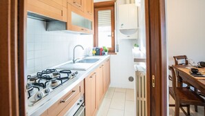 Une cuisine compacte avec des meubles en bois, une cuisinière à gaz et un coin repas comprenant une table et des chaises.