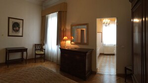 A hotel room with a bed, a desk, a chair, a mirror, and a window with curtains. - Oriuolo Giotto (Florence)
