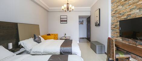 A hotel room with two beds, a TV, a desk, and a brick wall.