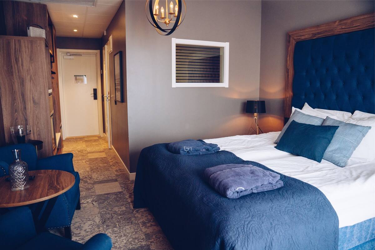 Ein Hotelzimmer mit einem großen Bett, einem Holzschrank, einem kleinen Tisch mit Stühlen und einer Kandelaber.