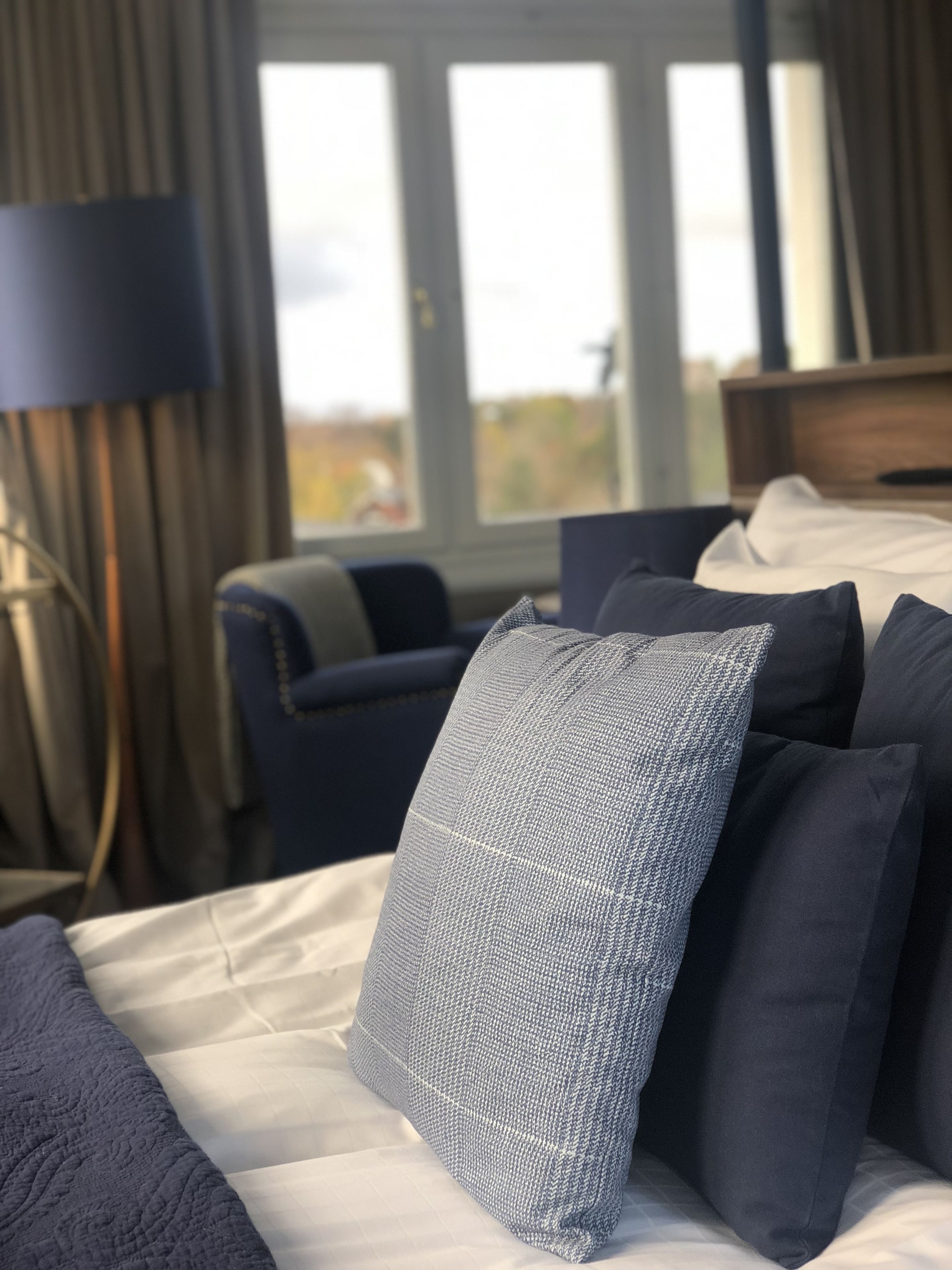 Una habitación de hotel con una cama, una silla y una lámpara.