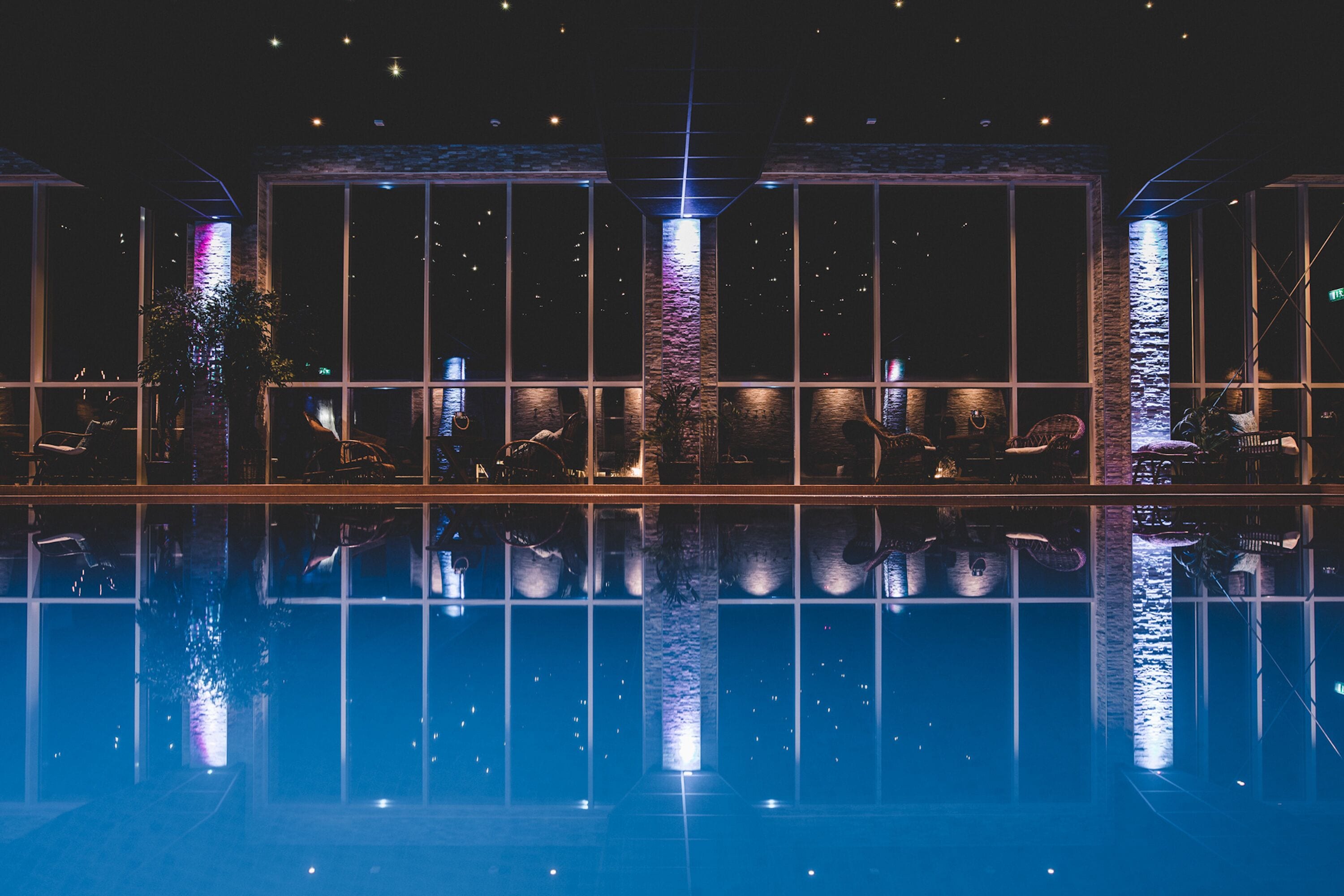 A pool area with clear reflections, large windows, and a modern architectural design.