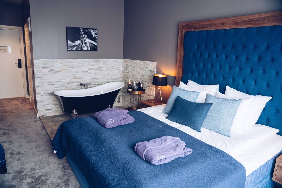 Ein Schlafzimmer mit einem großen Bett, einer Badewanne und einem Nachttisch mit Lampe.