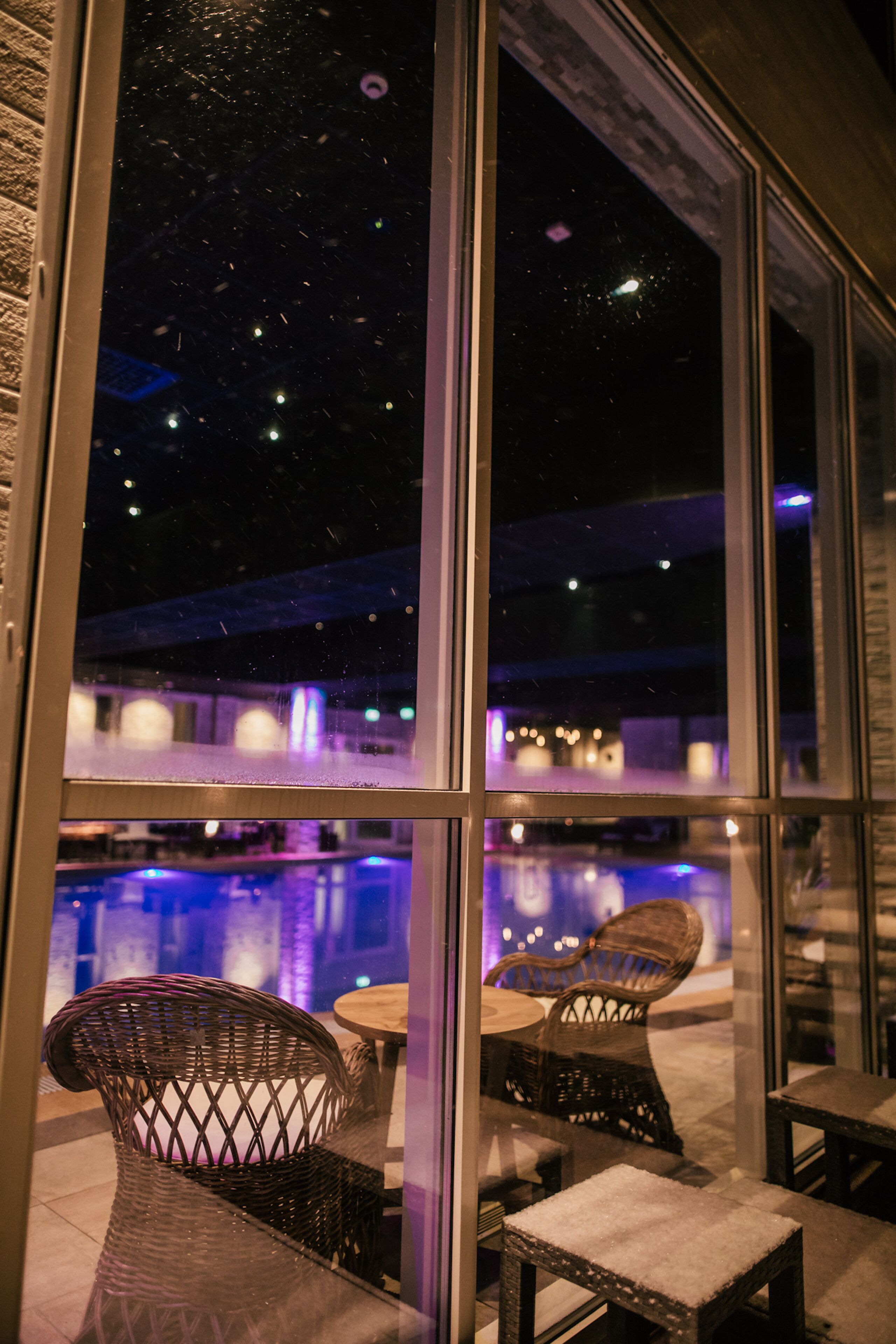 A view through a window of a restaurant with outdoor seating and a pool.