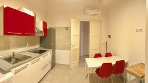 A compact kitchen with a microwave, sink, and a dining area with red chairs. - Appartamento Sant'Ambrogio nel cuore di Firenze (Florence)