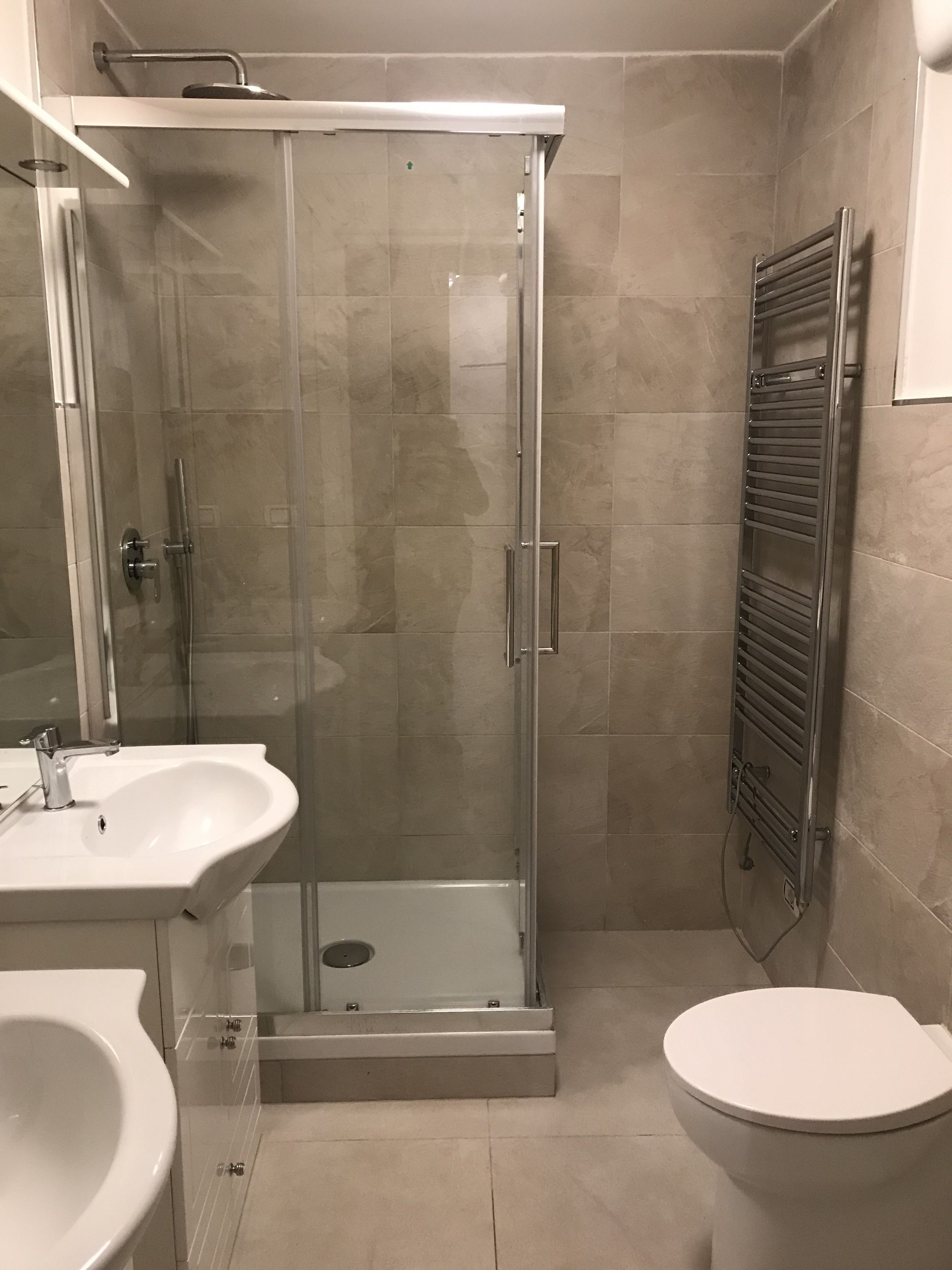 Un bagno moderno con doccia vetrata, lavandino bianco e un water.