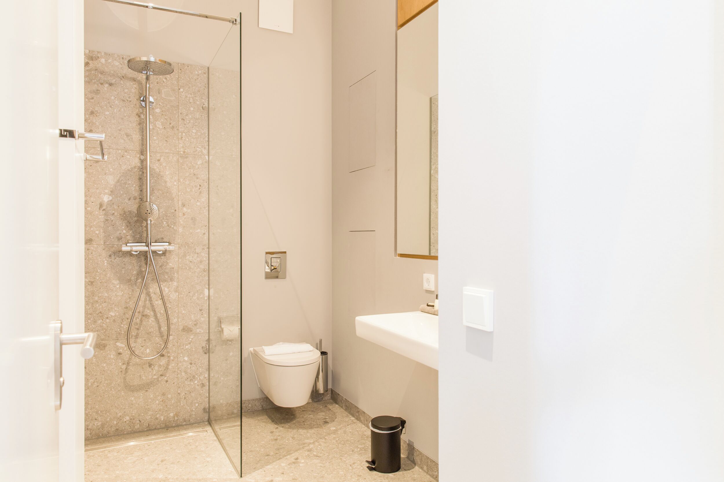 Een moderne badkamer met een douchecabine van glas, een toilet en een wastafel.