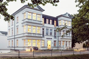Un edificio de varios pisos con un estilo arquitectónico clásico, que presenta una entrada destacada con la inscripción 