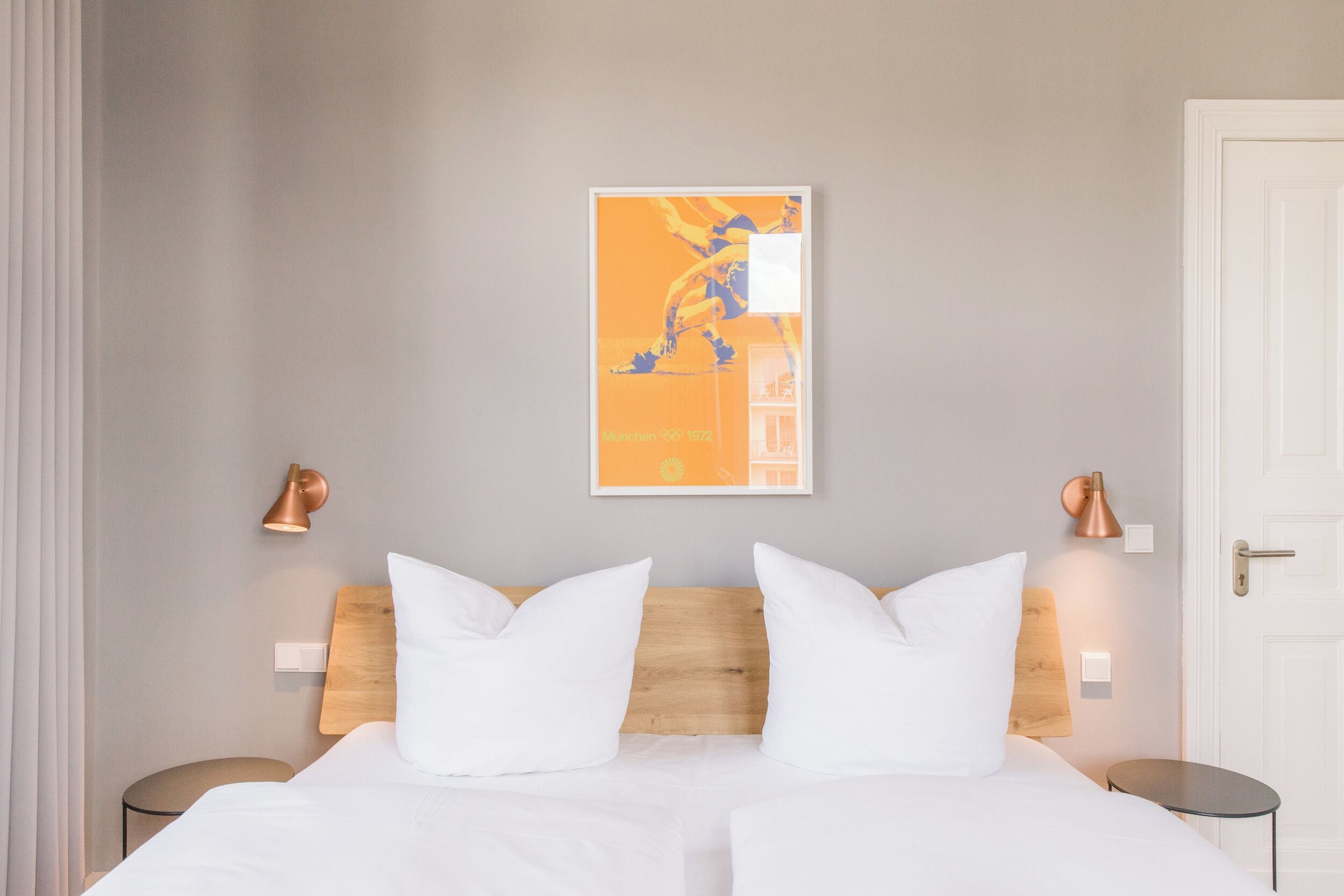 A hotel room with a bed, two bedside tables, a wall-mounted lamp, and a framed picture on the wall.