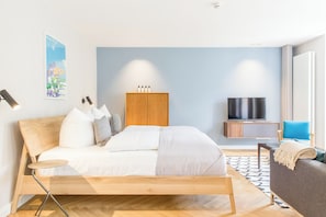 Ein modernes Schlafzimmer mit einem Holzbett, einem Fernseher, einem Kleiderschrank und einer Couch.