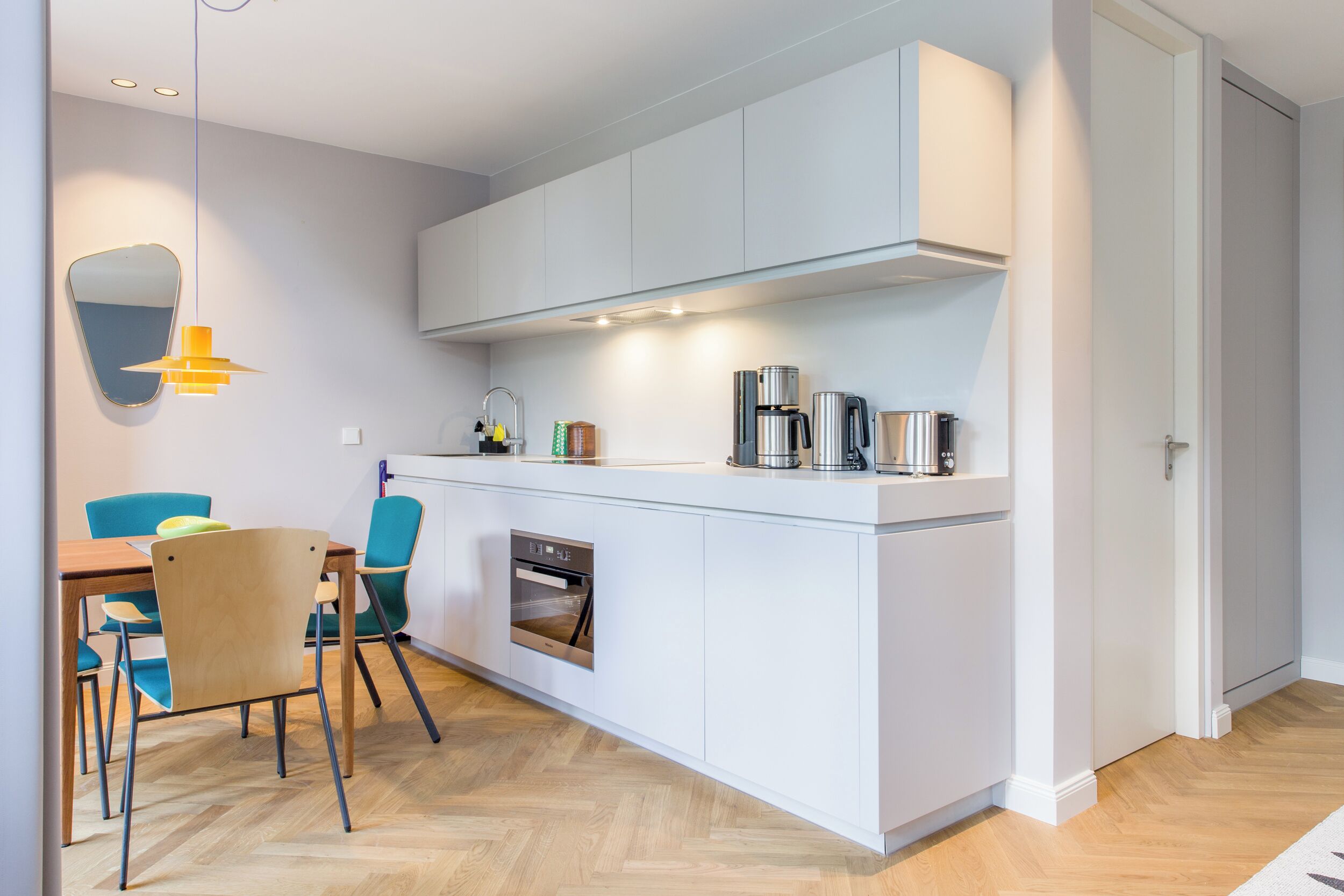 A modern kitchen with white cabinetry, a built-in oven, and a coffee maker.