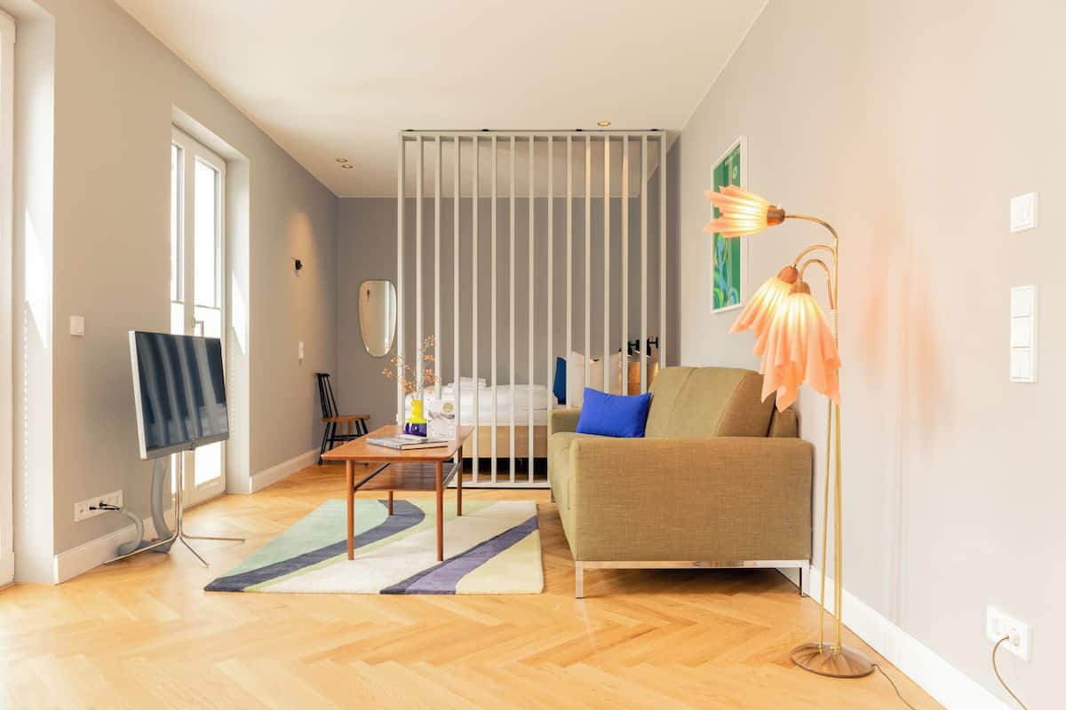 Un salon moderne avec un canapé, une table basse, un téléviseur et une lampe sur pied.
